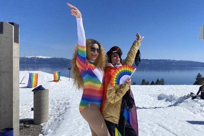 Two people in rainbow flags skiing