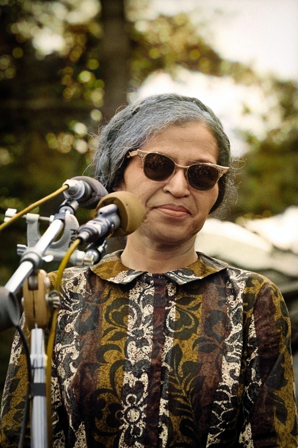 Black woman wearing sunglasses in front of a microphone