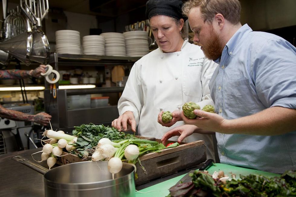 chef Nat Stratton-Clarke in the kitchen picking through a tray of fresh vegetables.