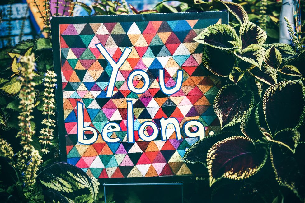 a colorful mosaic board that reads you belong.
