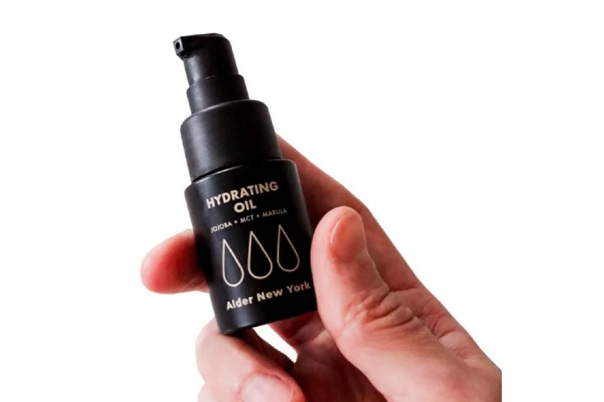 person holding a bottle of Alder's Hydrating Oil.