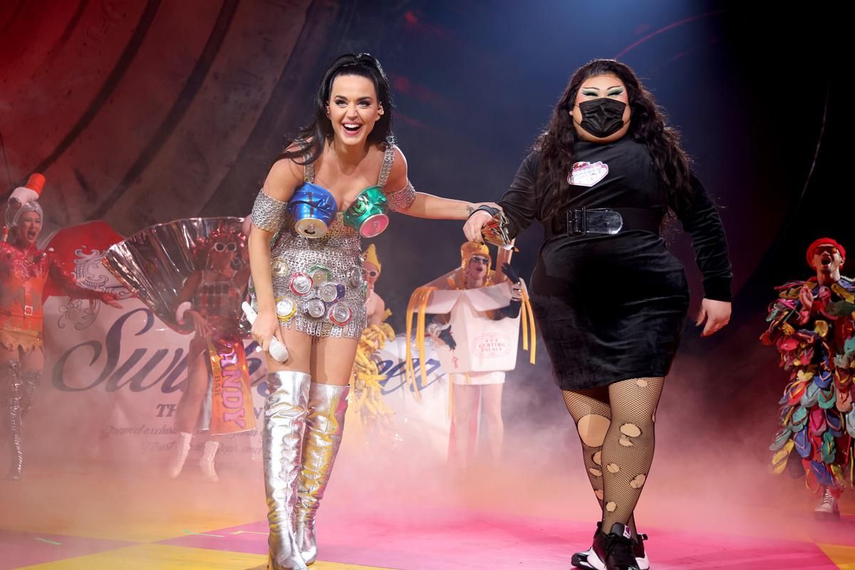 katy perry on stage with a masked woman in black.