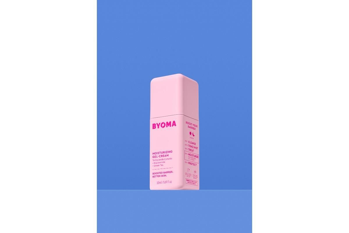 Pink bottle of BYOMA Moisturizing Gel Cream against a blue background.