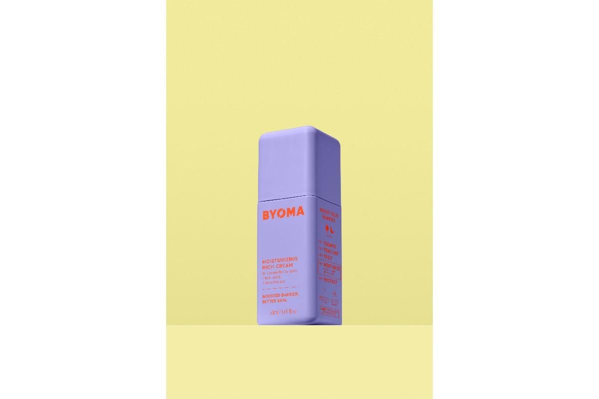 Purple bottle of BYOMA Moisturizing Rich Cream against a yellow background.