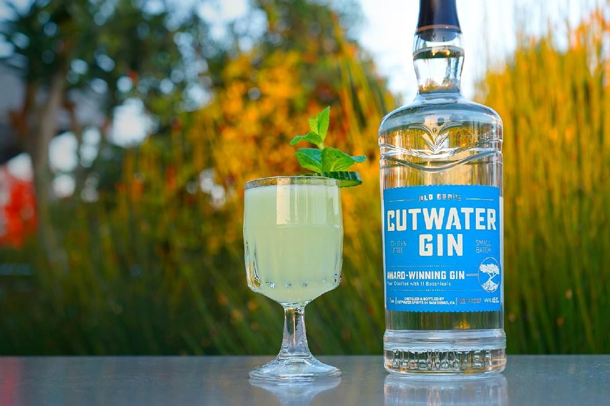 Cutwater gin and a light green cocktail sitting on a table outside.