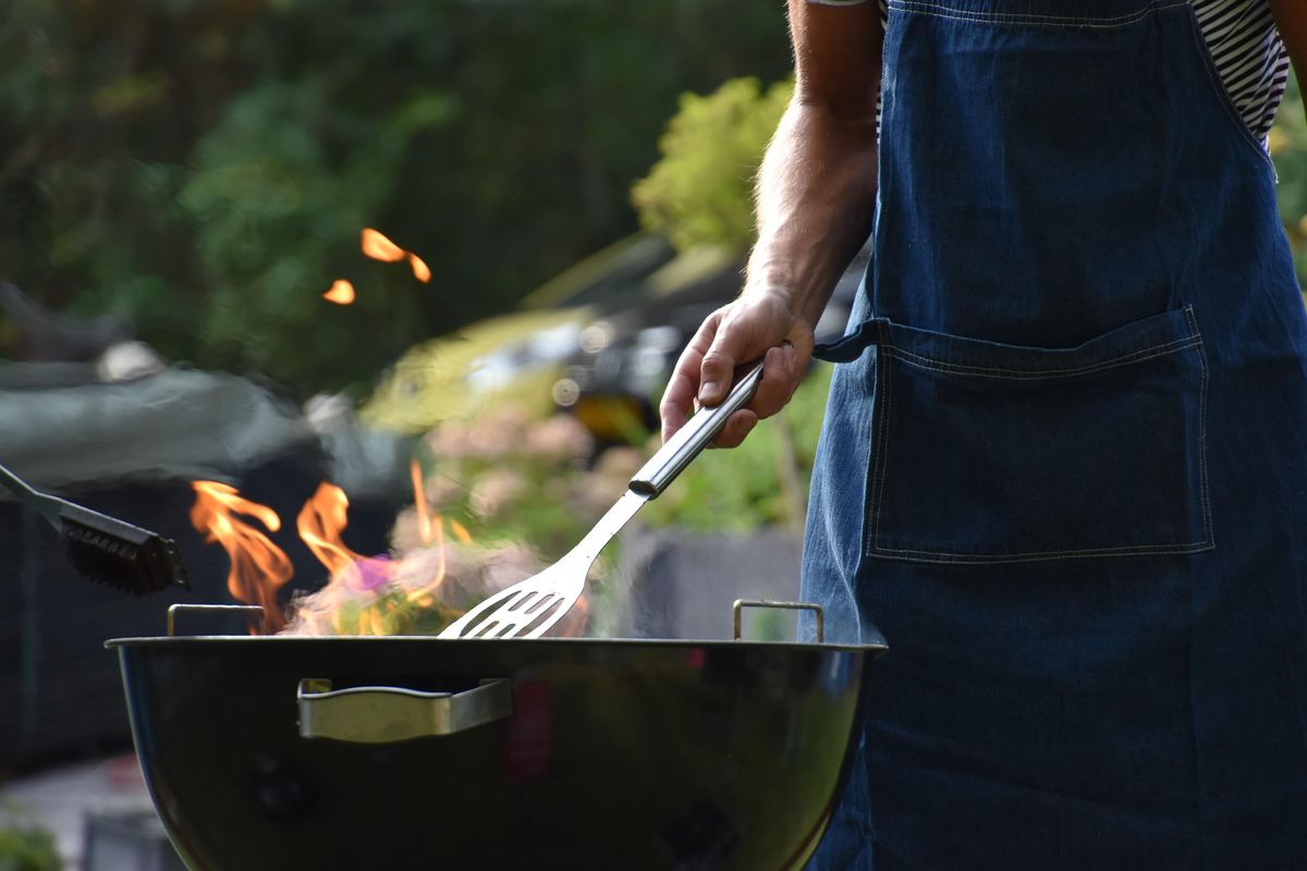 man standing over a grill.