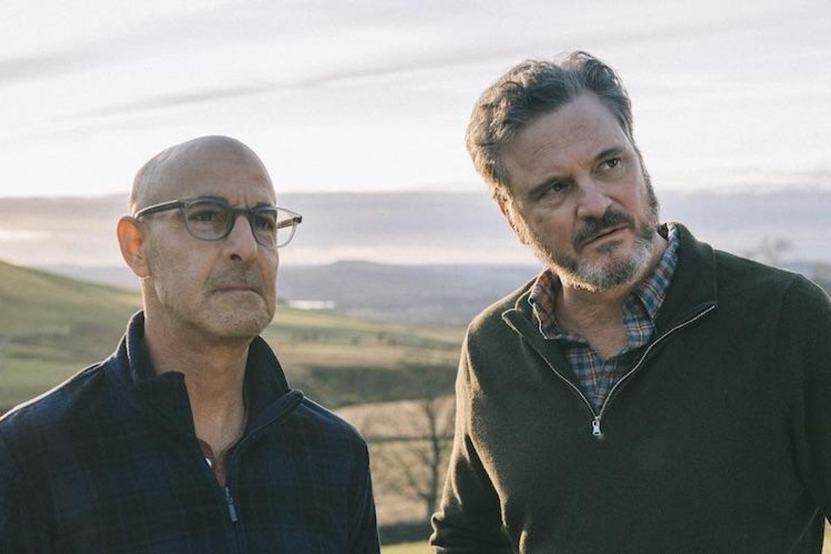 Stanley Tucci and Colin Firth in the movie Supernova standing outside in a field.