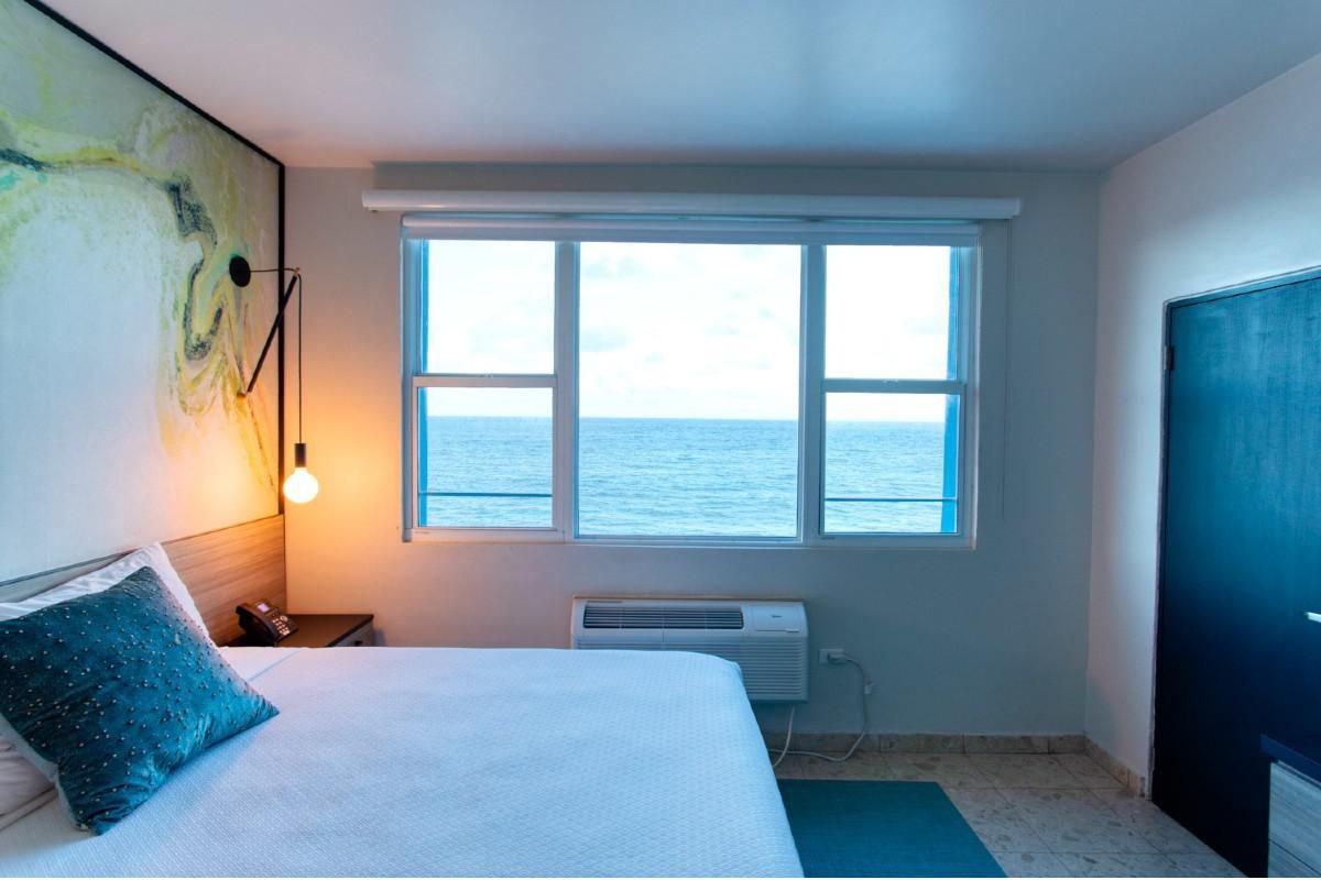 hotel room with a queen bed overlooking the ocean.