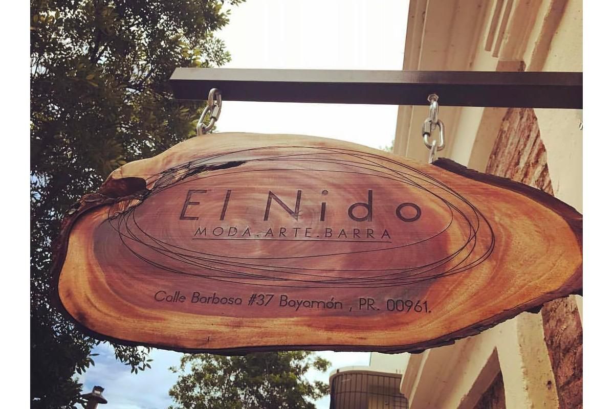 hanging wood sign with El Nido Moda arte barra and the address inscribed into it.