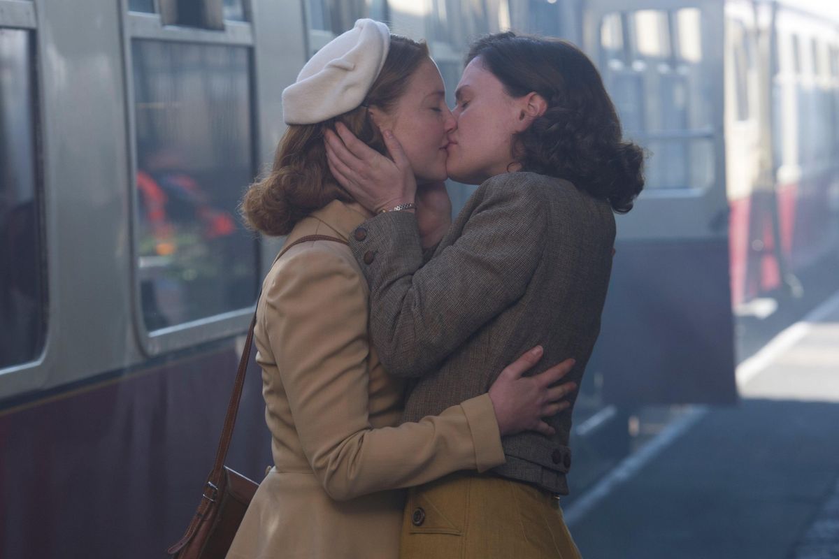 two women kissing on a train platform.