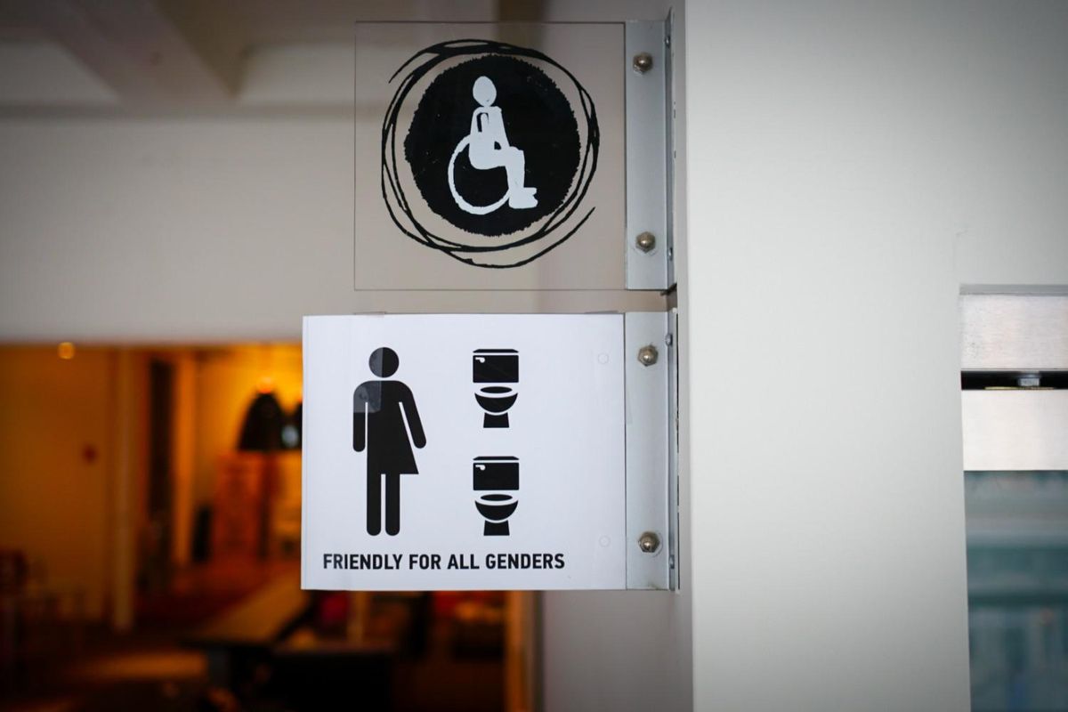 sign with a 'friendly for all genders' image showing a person in a wheelchair, and a person with half a dress and pants on.
