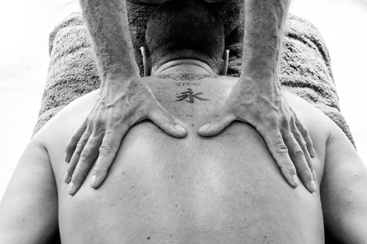 black and white image of a man massaging the back of another man.