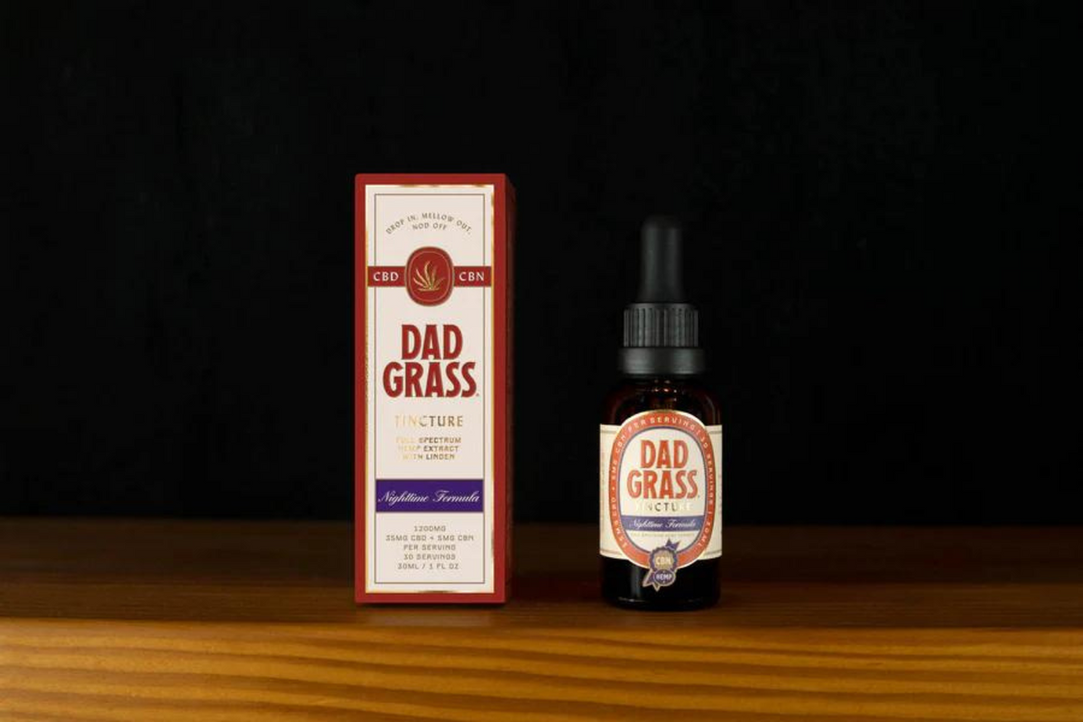 Dad Grass box and tincture bottle sitting on a wooden table.