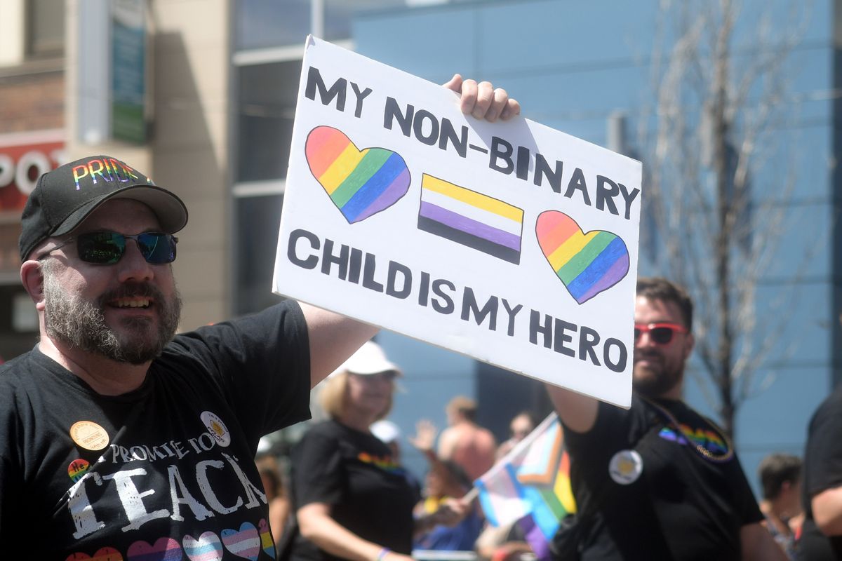 a man holding a sign reading my non-binary child is my hero at Chicago Pride.