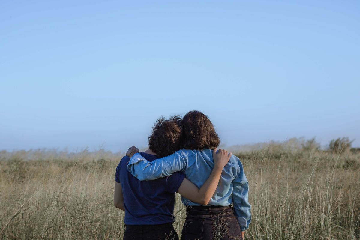 women hugging in a field.