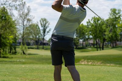 man in white t-shirt and black shorts holding golf club