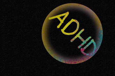 Black background with splotchy colored circle with the Letters ADHD inside