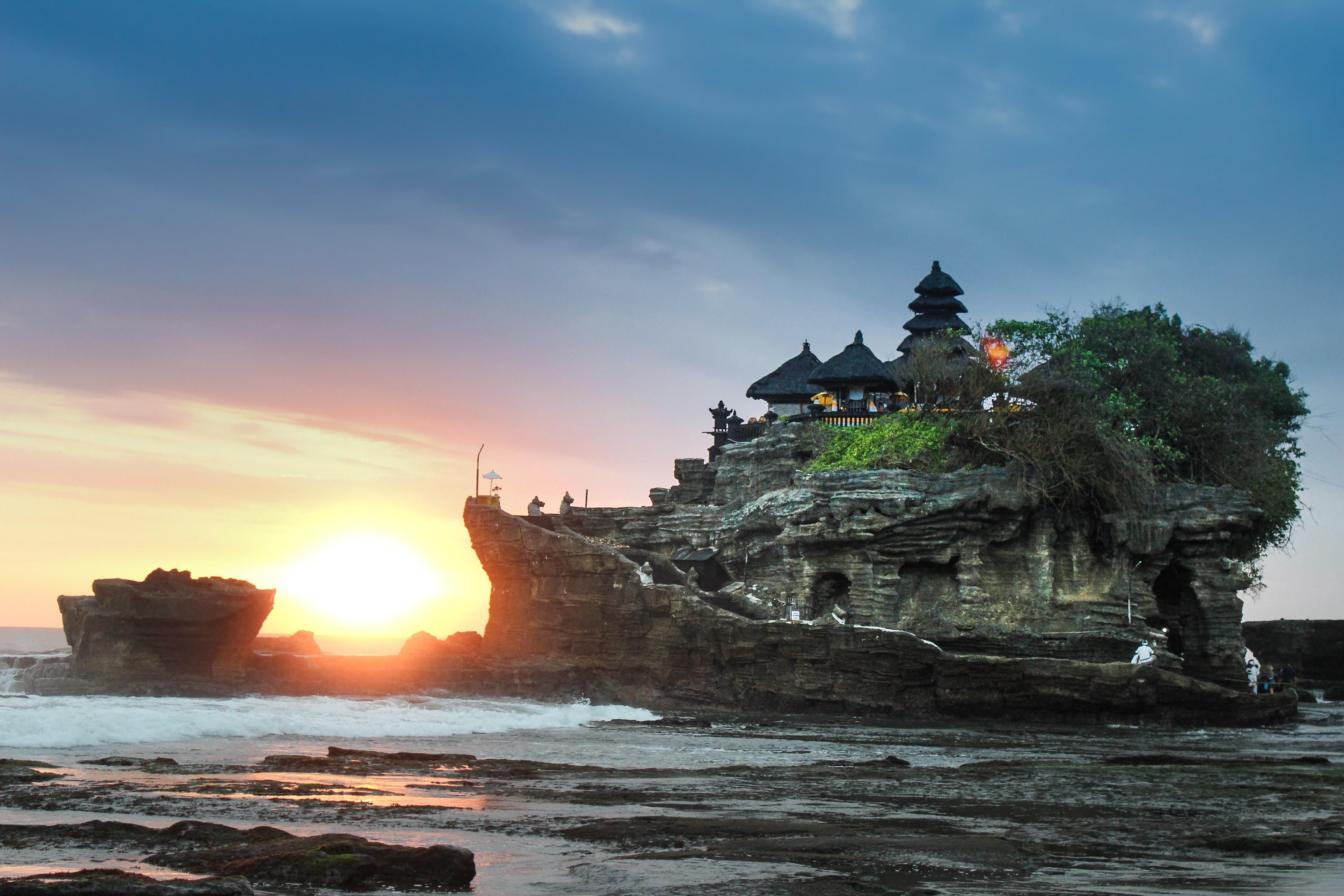 temple in Bali on gray rock hill with the sunset in the background.