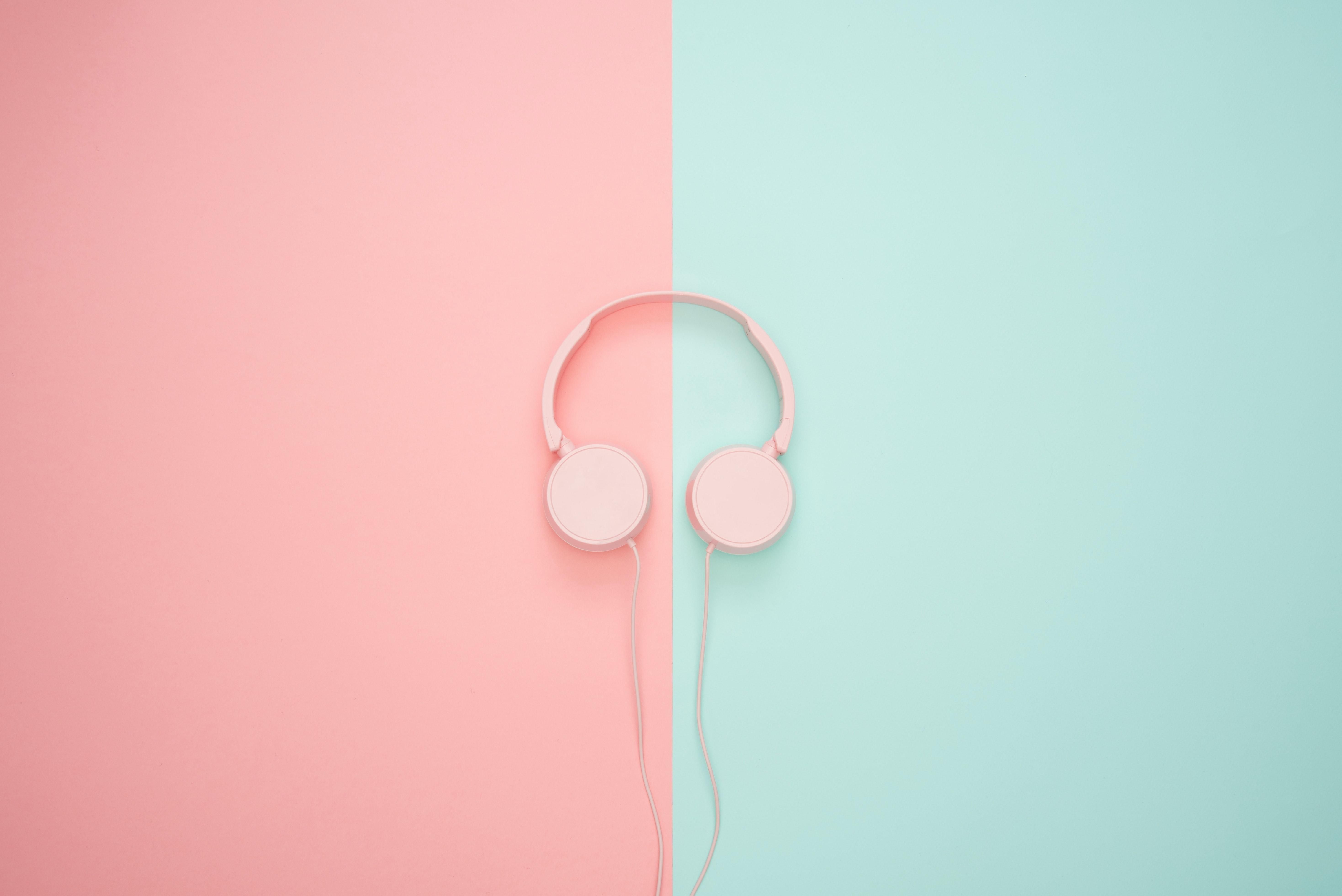 pink corded headphones against a pink and blue background.