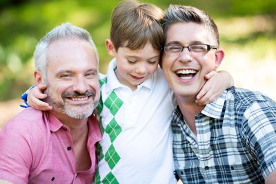 Two Gay Dads with Son hugging them.