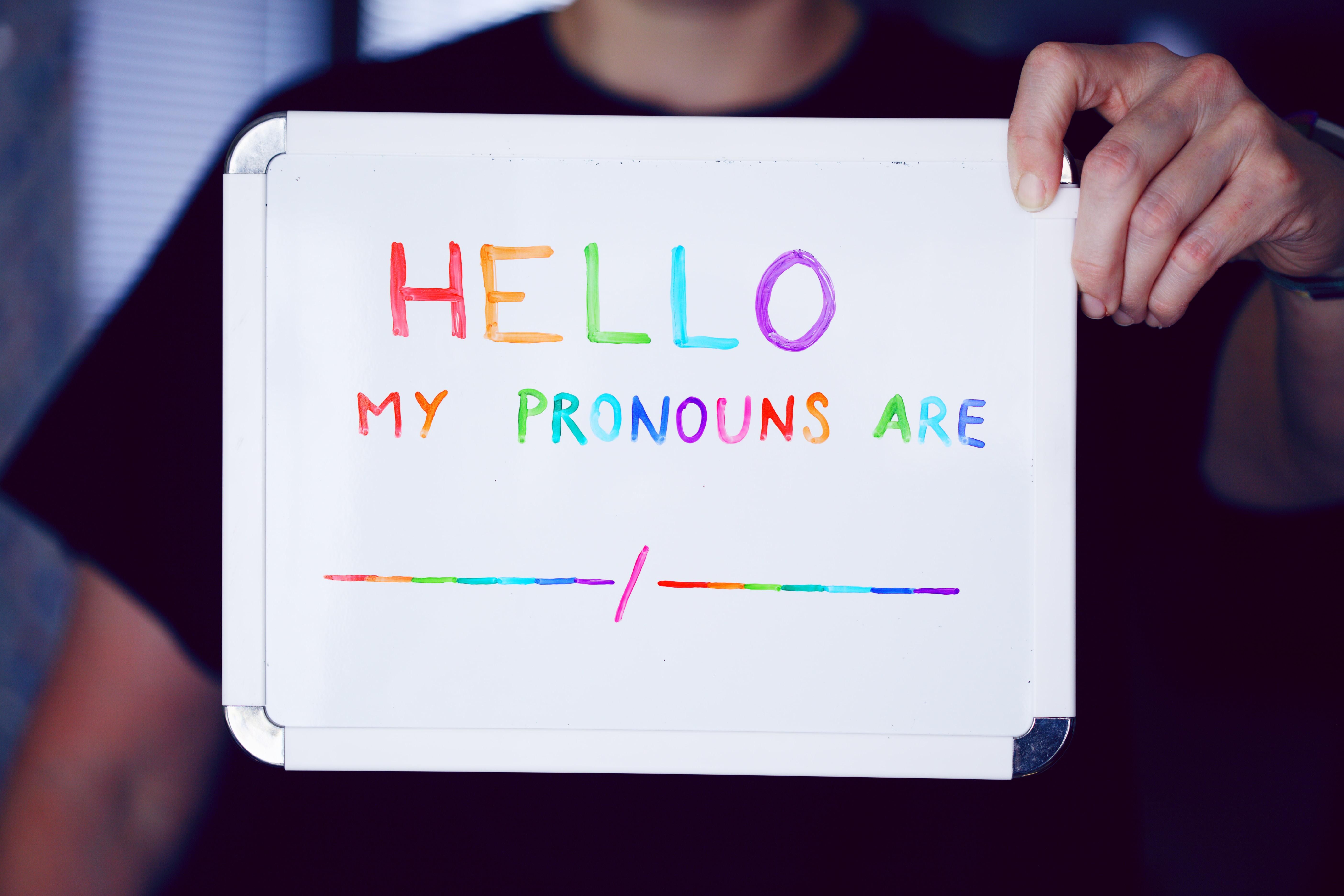 Person holding white printer paper reading Hello My Pronouns Are ___/_____