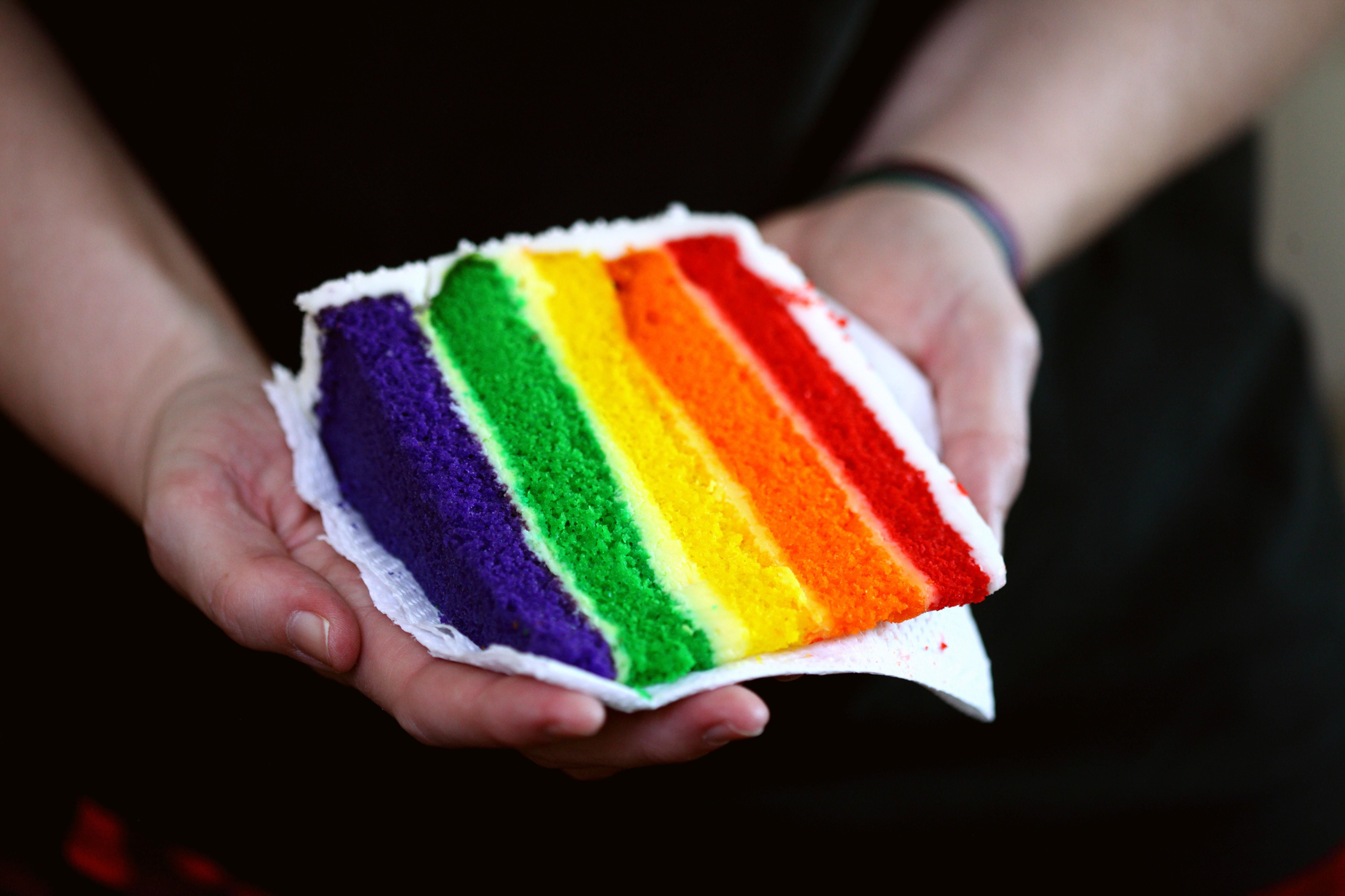 person holding a rainbow-layered cake.