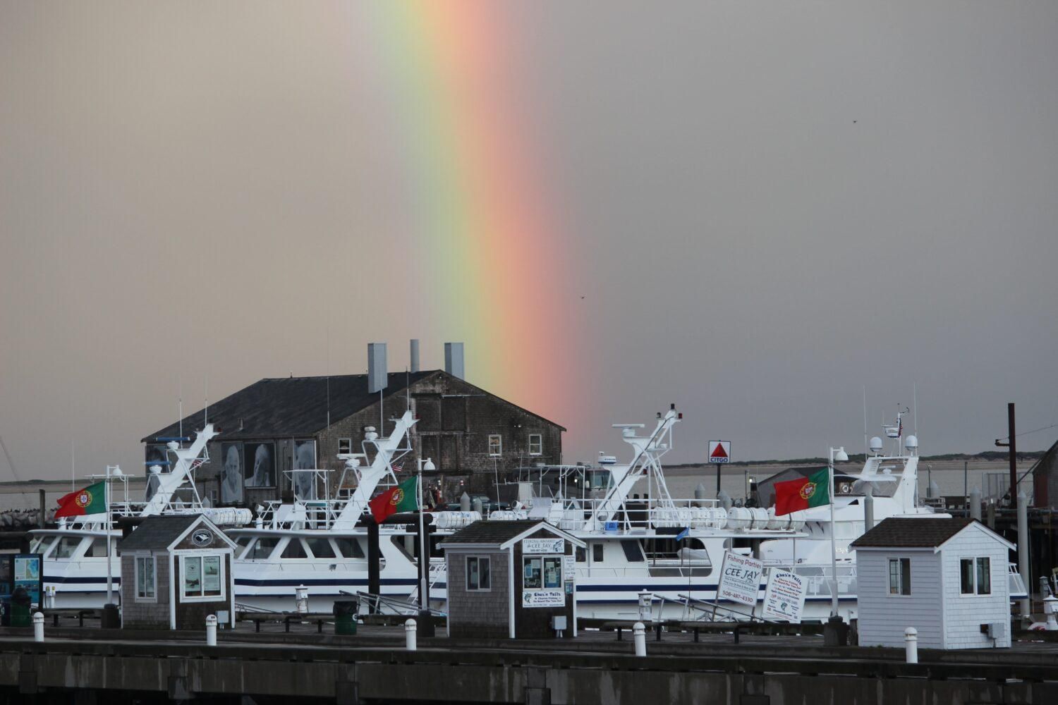provincetown harbor in the rain with a rainbow.