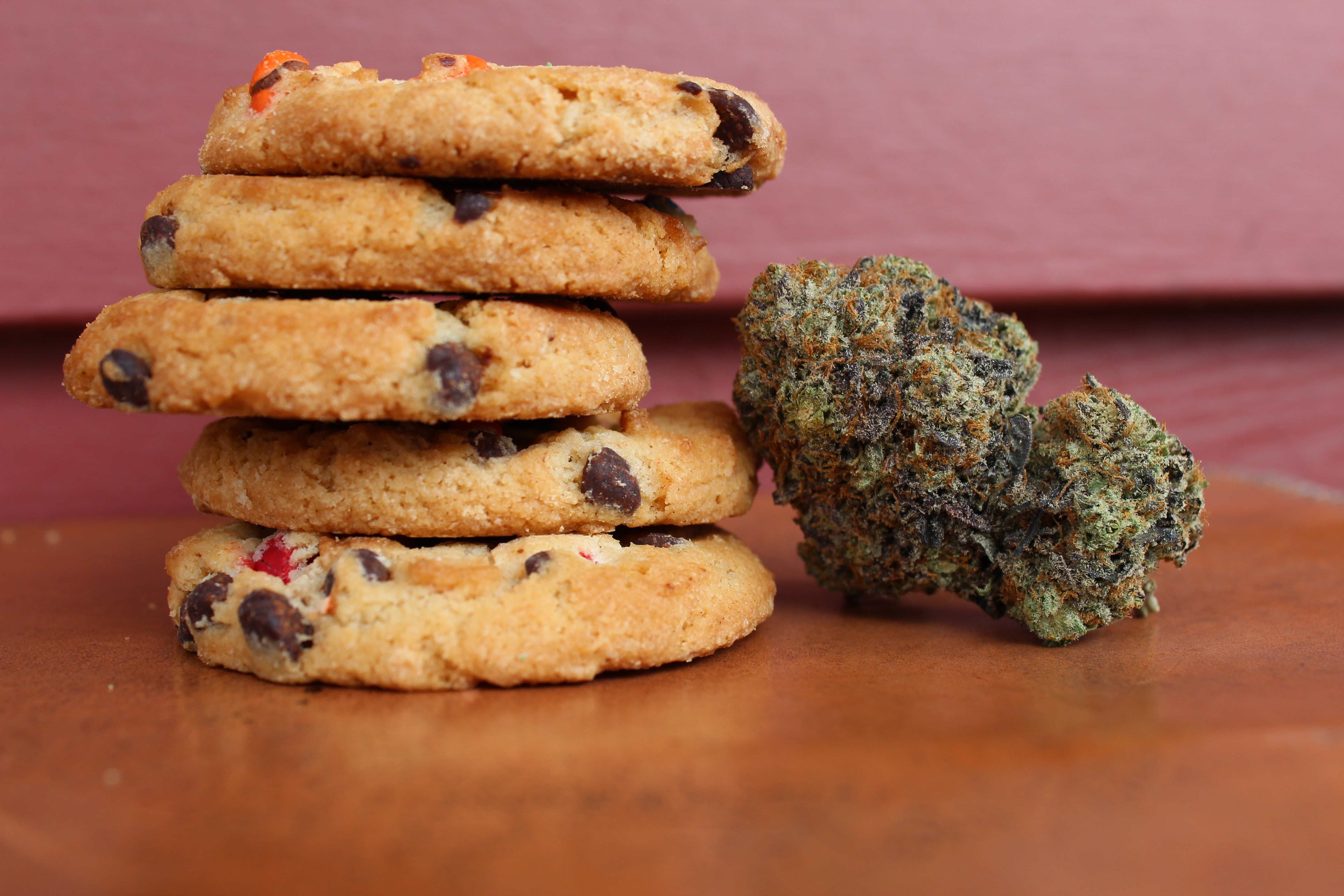 5 cookies stacked on top of each other next to a cannabis flower.