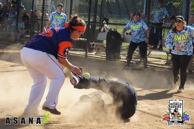 softball catcher tagging a runner at home plate as the runner falls.